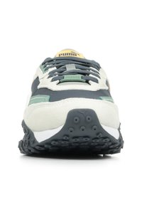Sneaker Puma con tomaia grigia, dettagli crema, chiusura con lacci, particolari verdi e suola nera testurizzata con motivi circolari visibili.