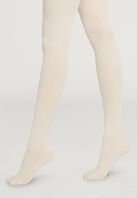 Collant beige a coste realizzati in un morbido e elasticizzato tessuto, caratterizzati da un design senza cuciture e una texture confortevole, adatti a vari completi.