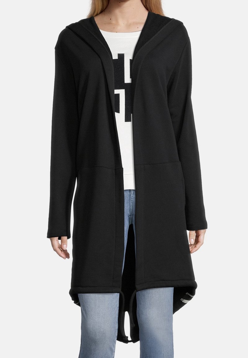 Cárdigan negro con capucha, hecho de una tela suave, con un frente abierto, mangas largas y un bajo curvado. Estampado gráfico blanco debajo.