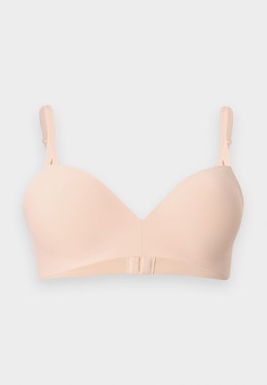 Sujeción con copa moldeada lisa color beige claro, con tirantes ajustables y cierre de gancho y ojo en la parte frontal sobre un fondo liso.