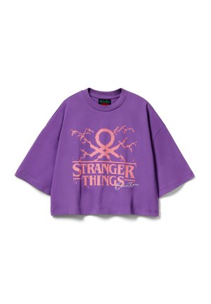 Fialové krátké tričko z bavlny s výrazným růžovým nápisem "STRANGER THINGS" a dalšími designovými prvky. Volný střih a krátké rukávy.