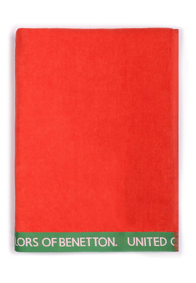 Serviette rouge en éponge avec une texture douce, présentant une bande verte en bas avec des lettres blanches qui disent "COLORS OF BENETTON. UNITED."