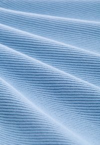 Tissu texturé bleu clair avec un motif côtelé, mettant en valeur de fines lignes et de douces plis, soulignant sa douceur et sa flexibilité.