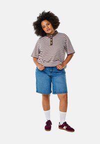 Polo à manches courtes à rayures avec col et boutons marron, associé à un short en denim bleu, des chaussettes blanches et des baskets bordeaux.