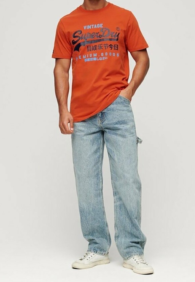 Orange T-shirt med blå grafik, parret med lyseblå lige jeans. Hvide sneakers fuldender outfittet. Minimalistisk design og blød stof.