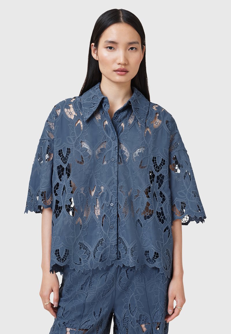 Spitzenhemd in Schieferblau, mit kurzen Ärmeln, einem Kragen und aufwendigen floralen Mustern. Halbtransparenter Stoff mit Knopfverschluss.