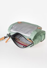 Grüne Softshell-Tasche mit einem grauen Netzfach, ausgestattet mit Reißverschluss, braunen Lederakzenten und mehreren inneren Fächern zur Organisation.