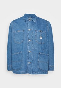 Modrá džínová bunda s klasickým límcem, čtyřmi předními kapsami a stříbrnými knoflíky. Obsahuje malou nášivku na levé kapse na prsou.