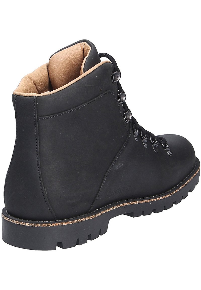 Schwarzer Lederwanderstiefel mit gepolstertem Kragen, robustem Schnürsystem, strukturierten Gummisohle und natürlichen Korkdetails an der Ferse.