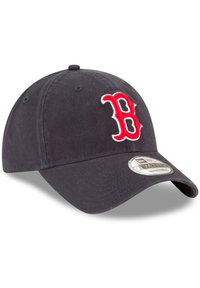 Navy baseball cap laget av bomull med justerbar stropp, med en rød brodert "B"-logo foran og en buet brem.