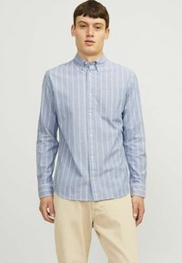 Šviesiai mėlynas marškiniai su plonomis vertikaliomis baltomis ir rožinėmis juostelėmis, su vienu kišenės projektu krūtinėje ir ilgomis rankovėmis.