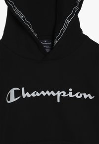 Sudadera negra con capucha que presenta un gran logotipo blanco de 'Champion' en la parte frontal. Tejido suave con capucha ajustable y detalles en blanco en el interior del cuello.