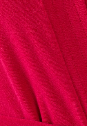 Tissu tricot fuchsia avec une surface texturée présentant des motifs de côtes verticales, tombant doucement et se chevauchant sur les bords.