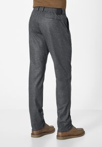 Graue Hose aus strukturiertem Stoff, mit geradem Bein-Design und Taschen; getragen mit braunen Schuhen. Merkmale eines schwarzen Etiketts am Bund.