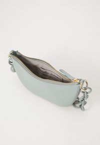 Sac en cuir bleu clair de forme arrondie, avec une fermeture éclair dorée et une finition texturée. Dispose d'une anse en chaîne et d'une doublure intérieure douce.