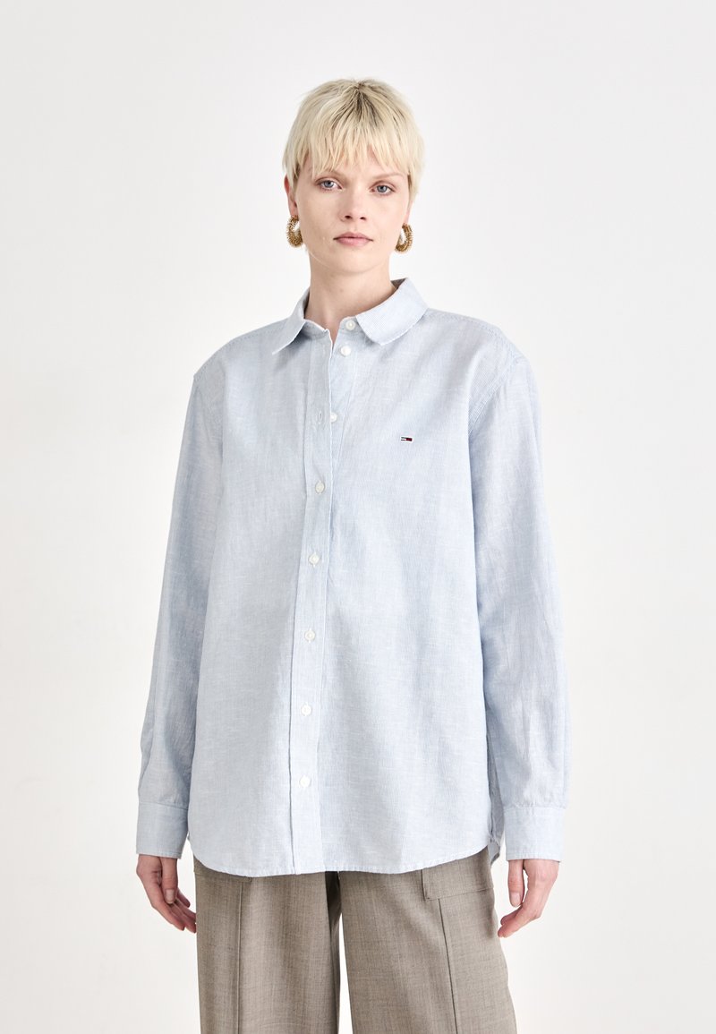 Camicia button-up azzurro chiaro con una sottile texture, maniche lunghe e colletto classico. Presenta un piccolo logo sul petto.