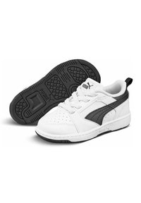Scarpe sportive bianche con tomaia in pelle liscia, dettagli neri, inserti forati e suola in gomma nera texturizzata. Presentano lacci e un logo.