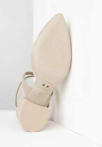 Beige shoe with a pointed toe, made of soft material. A low, sturdy heel features a textured sole and branded interior detailing. Size 37.