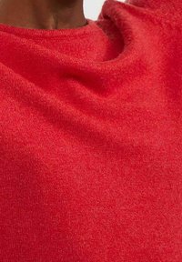 Pull rouge en tissu doux et texturé. Présente un col rond et un design drapé, avec une finition lisse et une répartition uniforme de la couleur.