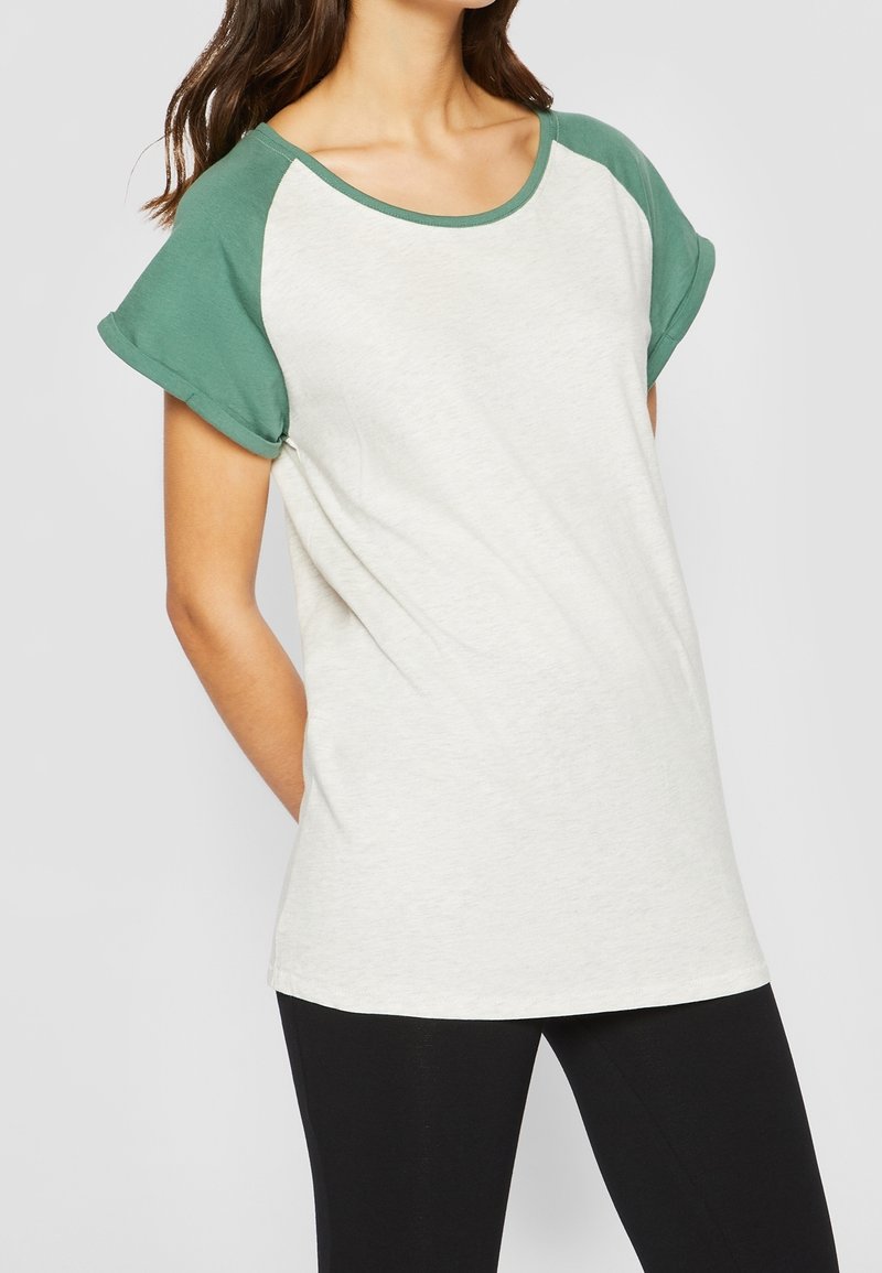 T-shirt gris clair avec des manches raglan vertes, col rond et coupe décontractée. Le matériau est doux, avec une texture lisse.