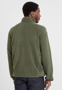 Olive green fleece pullover with a high collar, textured surface, long sleeves, and a relaxed fit. Visible stitching along the hem.