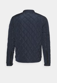 Navy quilted jacket with a diamond pattern, featuring a stand collar and zippered side pockets. Smooth, lightweight material.
