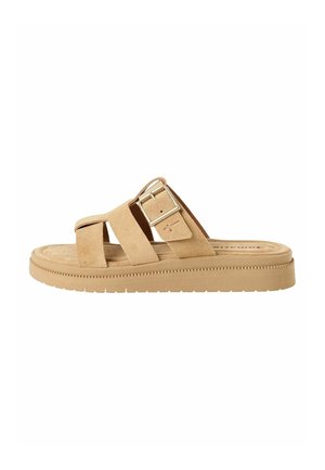 Zamszowy, brązowy klapek z dwiema skrzyżowanymi paskami i ozdobną sprzączką. Płaska podeszwa z teksturowanym bieżnikiem dla lepszej przyczepności i komfortu.