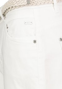 White cotton pants featuring a subtle logo tag, metal button details, and visible stitching. The fabric has a smooth texture.