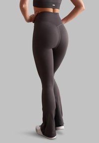 Leggings a vita alta a coste in grigio scuro, con fondo svasato e una texture liscia e elastica. Abbinati a sneaker bianche.