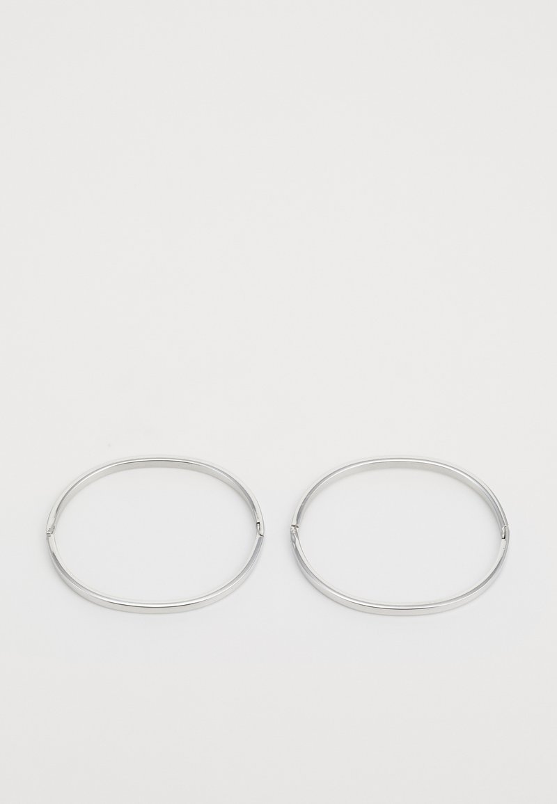 Pendientes de aro de metal plateado con un diseño circular simple, textura suave y un mecanismo de cierre para asegurar.