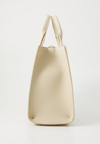 Sac en cuir beige avec une surface texturée, doté de deux poignées courtes et d'une forme rectangulaire, ouvert en haut avec un matériel minimal.