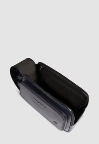 Zwarte en grijze leren reistas met rits en meerdere compartimenten open, die de interne opbergruimtes toont.