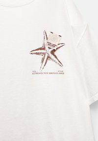 T-shirt en coton blanc avec un graphique d'étoile de mer marron et le texte "SEA STAR ASTROPECTEN IRREGULARIS" en dessous. Étiquette visible.