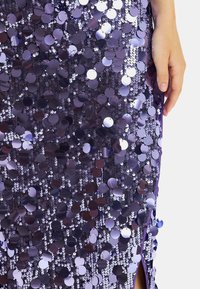 Fioletowa sukienka z cekinami, z wzorem okrągłych cekinów w różnych odcieniach, gładką teksturą i bocznym rozcięciem dla dodatkowego efektu.