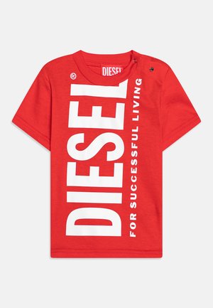 T-shirt rouge à manches courtes pour tout-petit avec un grand texte vertical blanc "DIESEL" et un plus petit texte "FOR SUCCESSFUL LIVING" sur le devant, boutons-pression à l'épaule.