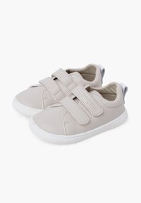 Beige nahast tossud kahekordse Velcro-ribaga, valge kummist tald, ümmargune varvas ja sile tekstuur, halli kontsapiirdaga.