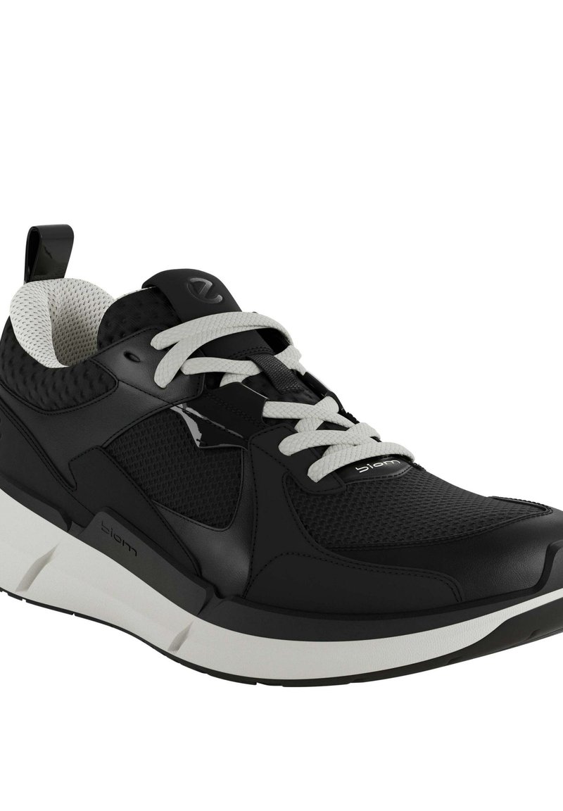 Czarne sportowe buty o siateczkowej cholewce, białych sznurówkach i wyściełanym kołnierzu. Podeszwa jest gruba i biała z czarnymi akcentami oraz oznakowaniem.