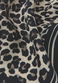 Tkanina se zvířecím vzorem leoparda s výraznými černými skvrnami na smetanovém pozadí, s měkkou texturou a kontrastním detailem námořnické pruhy.