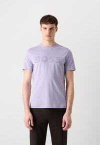 T-shirt en coton violet clair à manches courtes, avec le mot "BOSS" affiché en évidence dans une teinte plus foncée à l'avant.