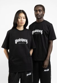 Svarte t-skjorter med kort erme har en hvit grafikk som leser "Wastedpang" og "Always Faithful," sammen med svarte joggebukser med en logo.