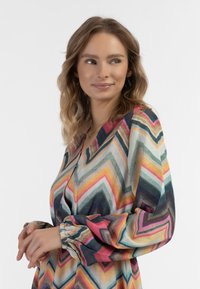 Värikäs mekko, jossa on geometristen sitruunoiden kuvio eri sävyissä vaaleanpunaista, sinistä ja vihreää, puffihihnoilla ja napitetulla edellä.