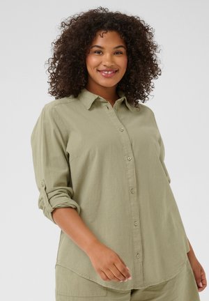 Lichtgroene blouse met knopen in een gestructureerde stof, met een kraag, verstelbare mouwen en een ronde zoom.