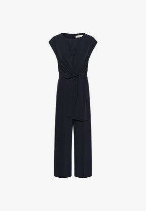 Combinaison marine à manches courtes, avec une taille ceinturée et une coupe à jambes larges. Fabriquée en tissu lisse avec une fermeture éclair dissimulée dans le dos.