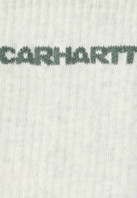 Světlý šedý pletený materiál s výrazným tmavě zeleným nápisem "carhartt". Hladká textura s jemným melírováním a rovnoměrným prošíváním.