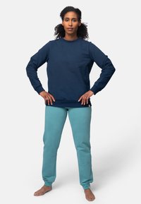 Navyblauwe katoenen sweatshirt met lange mouwen, ronde hals en geribbelde manchetten, gecombineerd met lichtgroene sweatpants met een taps toelopende pasvorm en een gladde textuur.