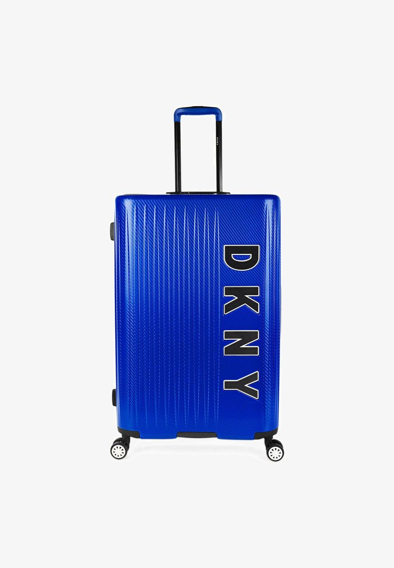 Maleta dura azul con estrías verticales, asa negra, logo de DKNY en letras blancas en negrita y cuatro ruedas giratorias.
