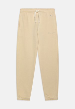 Pantalon de jogging beige avec taille et poignets élastiques, cordon de serrage à l'avant, poches latérales et logo Champion discret sur la cuisse gauche et la taille.