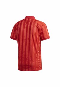 Jersey rojo de manga corta con franjas verticales, textura suave y cuello. Variaciones sutiles en tonos rojos añaden profundidad al diseño.