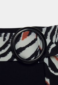 Cinto de tecido preto com fivela redonda em metal preto e uma sobreposição de tecido estampado em branco e preto com detalhes em laranja.