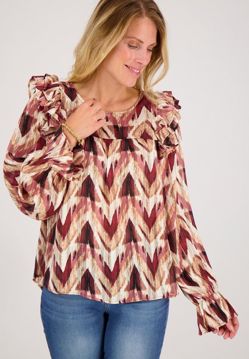Langzaam blouse met lange mouwen en gerimpelde schouders, met een meerkleurig zigzagpatroon in tinten bordeaux, crème en bruin. Zachte, vloeiende stof.